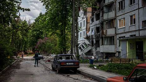 Ihmiset kävelevät tuhoutuneen asuinrakennuksen ohitse Harkovassa 15. toukokuuta.