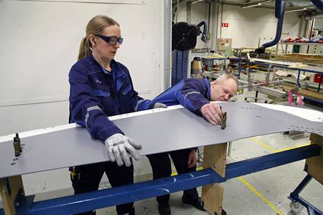 Sari Vähämäki ja Jouko Nyyssönen kiinnittävät sotilaskuljetuskoneen sivuvakaimen osaa telineeseen. 