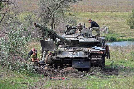 Ukrainalaisia sotilaita Venäjän armeijan hylkäämän panssarivaunun luona Harkovan alueella tiistaina.