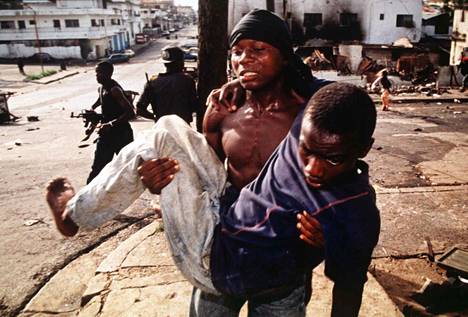 Taistelija kantoi haavoittunutta toveriaan Liberian pääkaupungissa Monroviassa riehuneen sodan aikana toukokuussa 1996.
