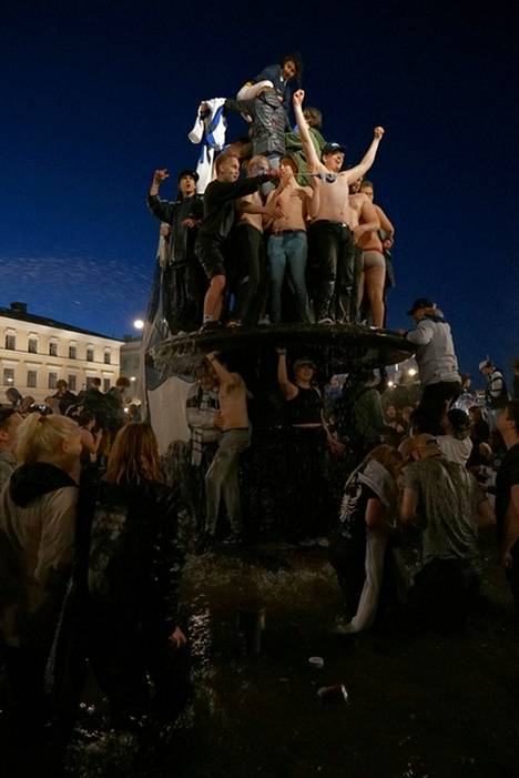 Joukko ihmisiä kiipesi Havis Amanda -patsaan päälle Helsingin Kauppatorilla.