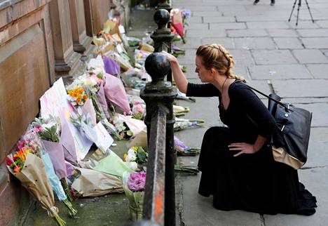 Nainen asetti kukkia uhrien muistoksi Manchesterin terrori-iskun tapahtumapaikalla tiistaina.
