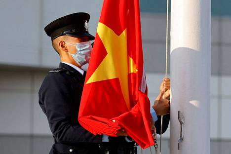Kiinalainen poliisi piteli Kiinan lippua toisen nostaessa sitä salkoon Hongkongissa 12. joulukuuta.