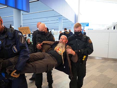 Poliisi ja rajavartiolaitos kantoivat mielenosoittajaa pois Helsinki-Vantaan lentokentällä lauantaina.