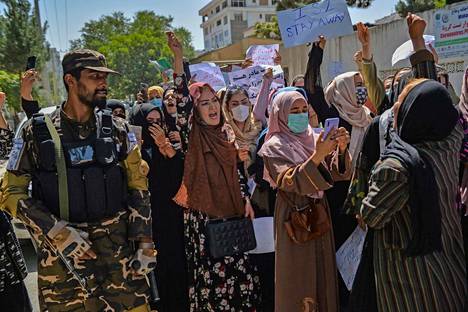Talebanin taistelija pitää vahtia, kun naiset osittavat mieltään Pakistania vastaan Kabulin suurlähetystön edustalla.