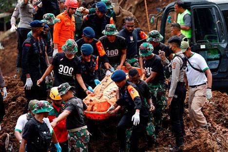 Rescue workers carry a body at the landslide site in Cugenang on Tuesday.