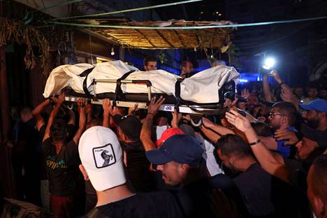 Ihmiset kantoivat veneturmassa kuolleen libanonilaismiehen ruumista Libanonin pääkaupungissa Tripolissa perjantaina.