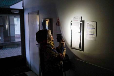Kampaamoyrittäjä Anita Paunonen tutki taskulampun valossa Pieksämäen Säästökeskus-kiinteistön ilmoitustaulua. Sähköt ovat poikki, kun laskuja ei ole maksettu.