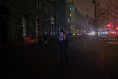 Nainen käveli sähkökatkojen pimentämillä kaduilla Kiovassa keskiviikkona.