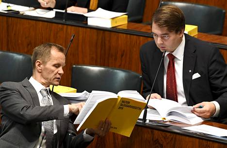 Perussuomalaisten kansanedustajat Mika Niikko (vas.) ja Ville Vähämäki tutkivat budjettikirjaa eduskunnan täysistunnossa vuonna 2018.