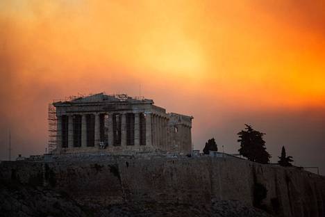 In the background of the Acropolis hill in central Athens, the sky glowed orange due to wildfires on Monday evening.