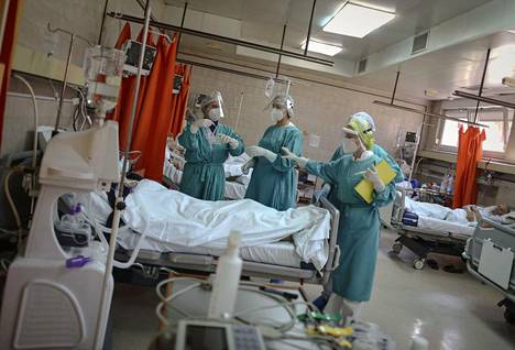 Hoitohenkilökunta koronaviruksesta kärsivän potilaan sängyn vierellä Belgradissa 26. maaliskuuta.