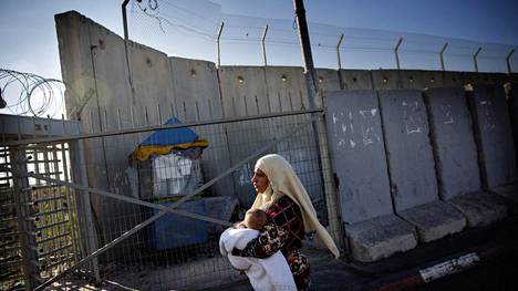Helsingin Sanomat kertoi syyskuussa 2014 Länsirantaa ympäröivän muurin vaikutuksesta palestiinalaisten elämään. Kuvassa Ramallahista Jerusalemiin matkalla ollut Reem Badran lapsensa kanssa Israelin armeijan Qalandiyan tarkastuspisteellä.