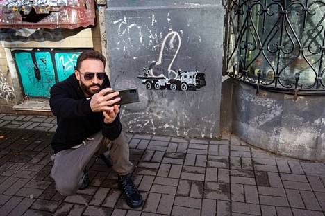 Mies otti selfietä Kiovassa Banksyn taideteoksen edessä. Taiteilija on käyttänyt jo olemassa olevaa peniskuvaa osana teosta. Peniksestä on tehty ydinkärki, joka seisoo venäläisessä, Z-merkillä varustetussa armeijan ajoneuvossa. 