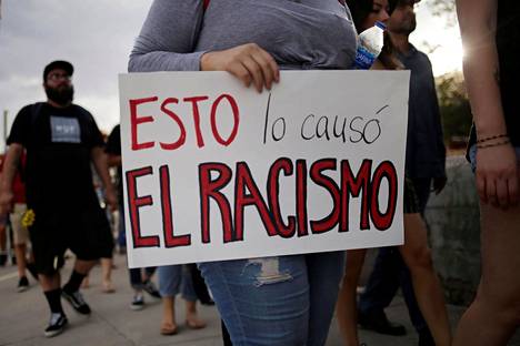 Viharikoksia vastaan mieltään osoittava nainen kantoi sunnuntaina El Pasossa kylttiä, jonka teksti kertoi rasismin olevan syy joukkoampumiselle.
