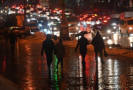 Jalankulkijat kulkivat ajovalojen valaisemalla jalkakäytävällä ruuhkaisen kadun varrella Kiovan keskustassa perjantaina. Sähköverkkoon kohdistettujen Venäjän iskujen vuoksi kaupungin metroliikenne oli poikki.