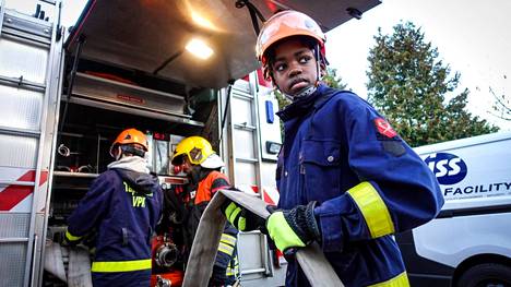 Patrick Österholm, 11, ottaa sammutusletkua ulos paloautosta vapaaehtoisen palokunnan harjoituksissa Helsingissä.