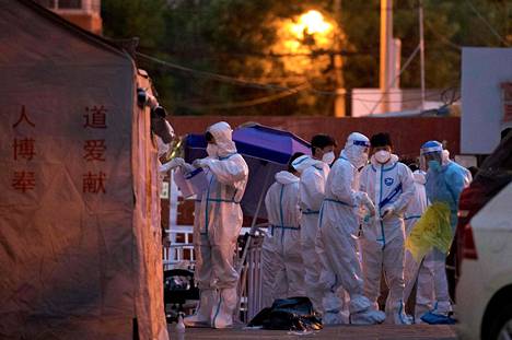 Terveystyöntekijät olivat pukeutuneet suojavarusteisiin työskennellessään eristykseen määrätyn pekingiläisen asuinalueen portilla keskiviikkona.