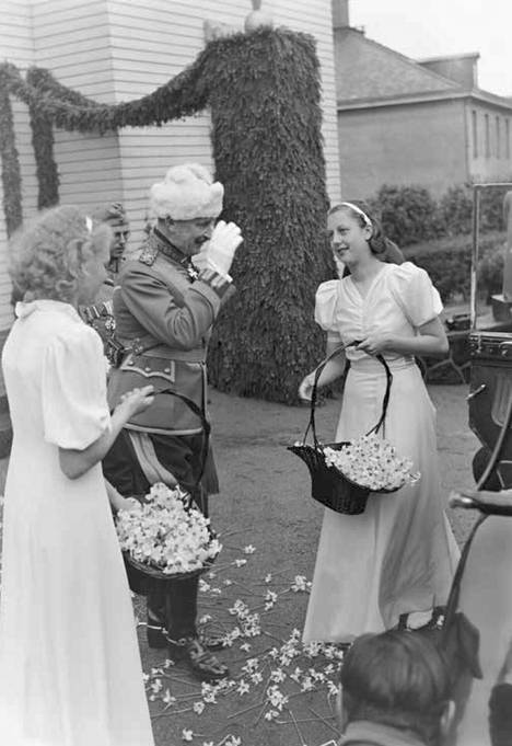 ”Jääkärien tyttäret” sirottelevat narsisseja sotamarsalkka Mannerheimin eteentämän astuessa ulos Kaivopuiston kodistaan 70-vuotissyntymäpäivänään 4.6.1937. – Kaikki artikkelin kuvat kirjan kuvitusta.
