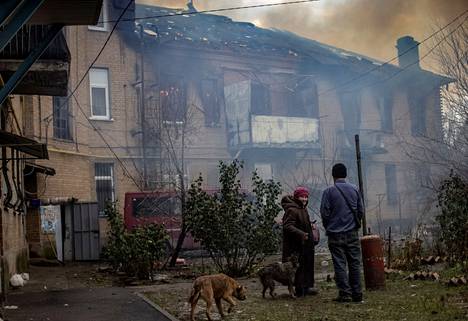 Оставшиеся горожане смотрят на то, как горит их дом. 9 декабря 2022 года. Фото: Евгений Титов / AFP
