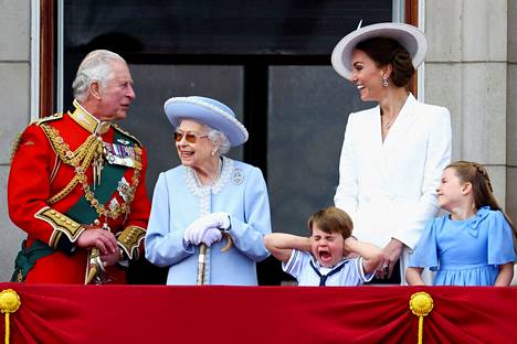 Prinssi Louis piteli korviaan palatsin parvekkeella viime kesäkuussa. Kuvassa myös syyskuussa kuollut kuningatar Elisabet, Charles, prinsessa Charlotte sekä lasten Catherine-äiti, jonka titteli on nykyään Walesin prinsessa.