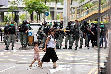 Äiti ja lapsi ylittivät katua mellakkapoliisien valvovan katseen alla heinäkuun alussa Hongkongissa.