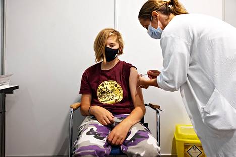 Sairaanhoitaja Lotta Kujala antaa koronarokotteen 12-vuotiaalle Lauri Backmanille Messukeskuksessa. Backmanin mukaan rokotus pisti vain hiukan.