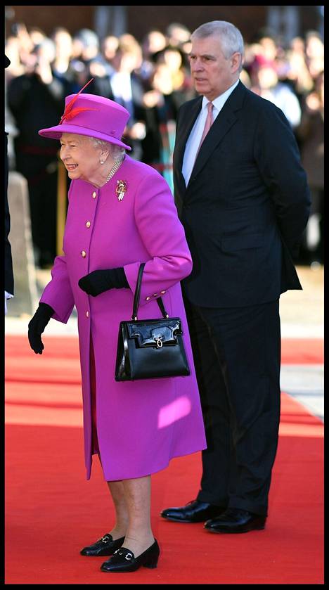 Kuningatar Elisabet ja prinssi Andrew joulukuussa 2018 Lontoossa. Kuningatar on pukeutunut kirkkaaseen violettiin asuun. Asusteena hänellä on helmikaulakoru sekä mustat hanskat, laukku ja kengät. 