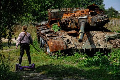 Teini leikkii venäläistankin vieressä Lukašivkan kylässä Pohjois-Ukrainassa.