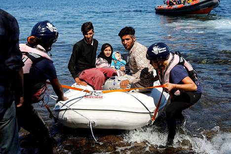 Avustusjärjestön työntekijät vetivät Afganistanista tulleiden siirtolaisten kumiveneen maihin Lesboksen saarella syyskuussa 2019.