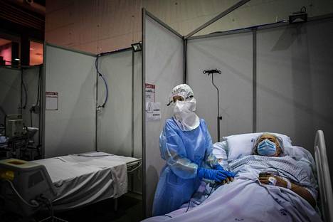 Terveydenhuollon työntekijä potilaan luona kenttäsairaalaksi muutetussa urheilustadionissa Portugalissa Portimãon kaupungissa. Portugali on yksi maista, joissa koronatartunnat ovat vähentyneet eniten kuluvalla viikolla.