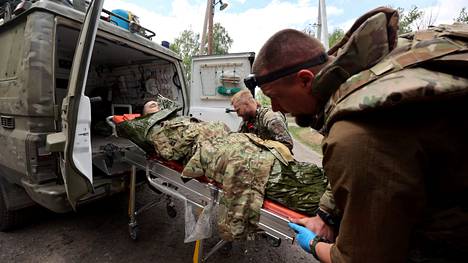Lääkintämiehet kantoivat Venäjän pommituksissa loukkaantunutta miestä evakuoitavaksi Harkovan lähistöllä viime sunnuntaina.