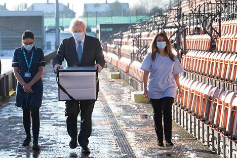 Britannian pääministeri Boris Johnson kantoi maanantaina Astra Zeneca rokotteita lontoolaisen Barnet FC -jalkapalloseuran stadionille, jota käytetään joukkorokotuskeskuksena.