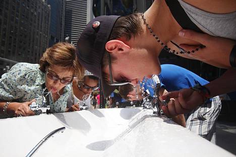 Ihmisiä juomassa vettä helteisenä kesäpäivä New Yorkissa.