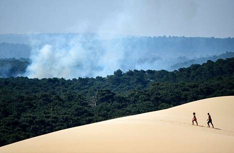 Kaksi ihmistä käveli lauantaina Pilatin dyynillä, Gironden alueella Lounais-Ranskassa metsäpalojen savutessa horisontissa.