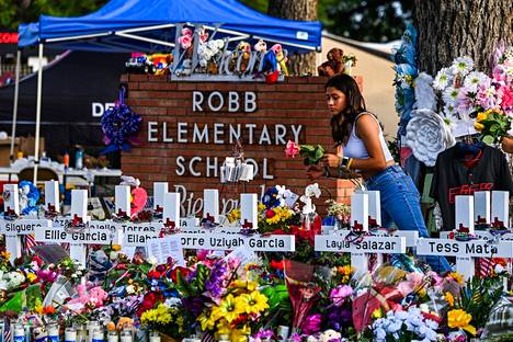Nainen laskemassa kukkia muistomerkille Robbin peruskoululla Texasin Uvaldessa.