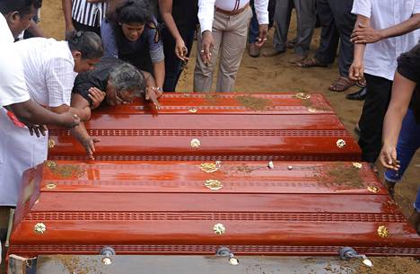 Nainen itki lastenlastensa arkkujen äärellä keskiviikkona, kun Sri Lankan pommi-iskujen uhreja haudattiin.