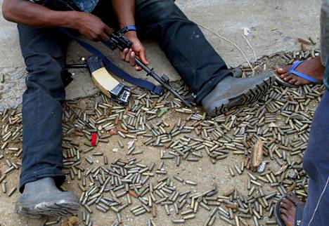 Kapinallisjoukkoihin kuulunut taistelija puhdisti asettaan hylsyjen keskellä Liberian pääkaupungissa Monroviassa elokuussa 2003.
