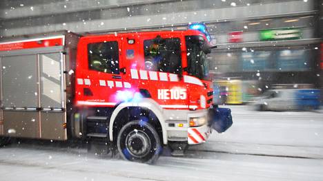 Paloauto ajaa lumimyräkässä raitiotiekiskoilla Helsingin Kaivokadulla vuonna 2018.