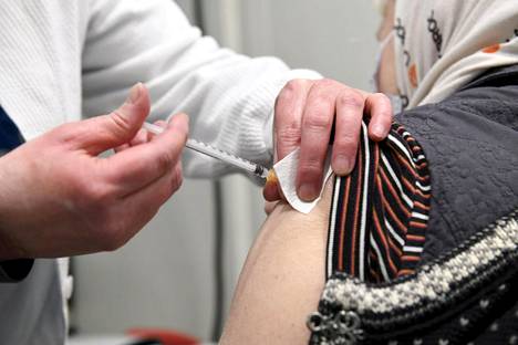Hoitaja antaa rokotuksen Helsingin kaupungin koronarokotuspisteessä Helsingin Messukeskuksessa helmikuussa.