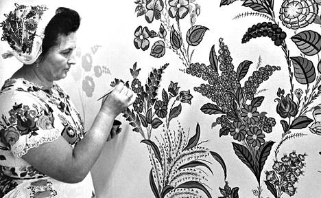Rouva Mariska Egry maalaamassa seinälle iloisia, tarkkaa silmää ja kättä vaativia kukkia. Seinää on paljon jäljellä Unkarin osastolla, jossa rouva Egry taiteilee messujen ajan.