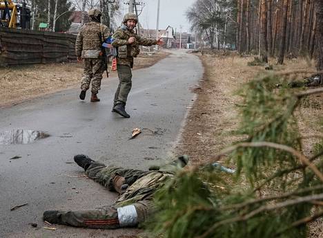 Ukrainalaissotilaat kävelivät kuolleen venäläissotilaan ruumiin ohitse pääkaupungin Kiovan ulkolaidalla 30. maaliskuuta. 