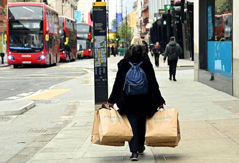 Nainen kantaa ostoskasseja Lontoon ydinkeskustan Oxford Streetillä 12. huhtikuuta, kun maa alkaa vähitellen purkaa koronarajoituksiaan.