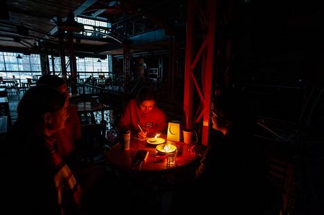 Ihmiset istuivat kynttilöiden valossa ravintolassa Lvivissä Länsi-Ukrainassa perjantai-iltana.