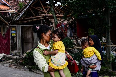 Women carried their children in front of the ruins of Sekalanwung village on Tuesday in Cianjur district, Java.