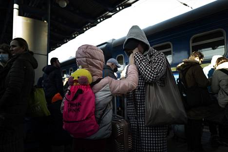 The daughter comforted her crying mother at the Kiev railway station.  In the backpack, the girl had a colorful plush toy. 