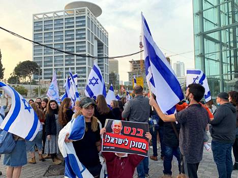Ziv Hakimi (vas.) ja puolisonsa Shachar (oik.) mielenosoituksessa Tel Avivissa keskiviikkona. Pariskunnan 7-vuotias esikoistytär pitelee kylttiä, jonka mukaan pääministeri Bennett on vaara Israelille