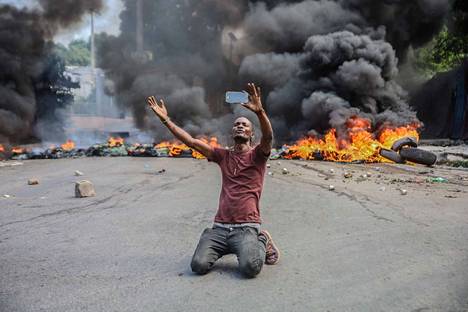 Haitilaismies kuvasi itseään palavien autonrengas­kasojen edessä pääkaupungissa Port-au-Princessa sieppauksia vastustavassa mielen­osoituksessa maanantaina.