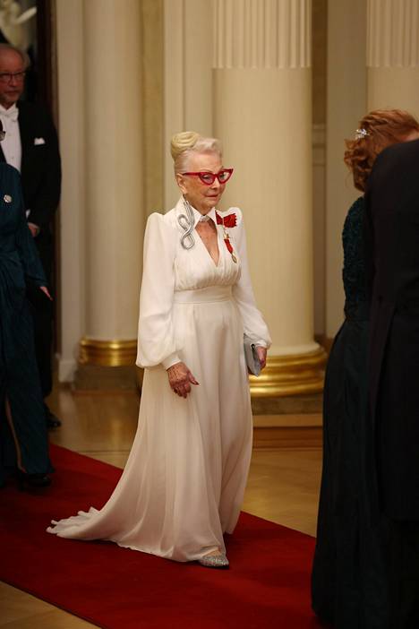 Актриса Сила Селла прошла по красной дорожке в белом платье, украшенном подплечниками и глубоким декольте. Я живу в дополняющих образ кошачьих очках.