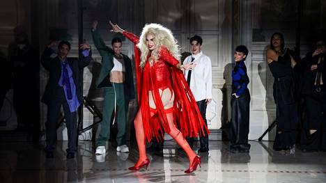 Muotisuunnittelija Ervin Latimer (edessä) juonsi Latimmer-malliston esitelleen muotishow’nsa Firenzen Pitti Uomo -messuilla. Latimer esiintyi draghahmossa, jonka roolinimi on Anna Konda.